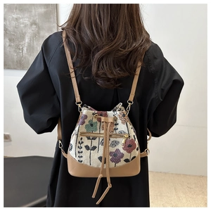 Floral jacquard bucket backpack with brown leather trim and front zipper pocket