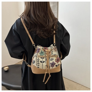 Detail view of floral jacquard bucket bag with brown leather straps and drawstring