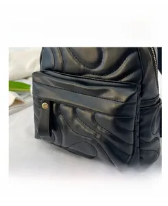 Detailed view of the black quilted backpack showing the wavy texture and front zip pocket