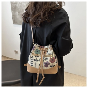 Detail of floral tapestry bucket bag with brown leather trim and drawstring closure