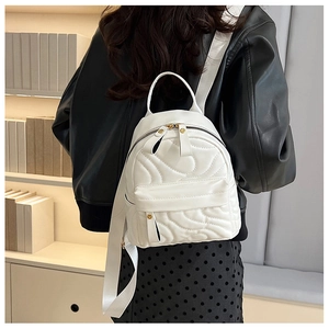 White quilted mini backpack with adjustable shoulder straps worn by model in a library setting