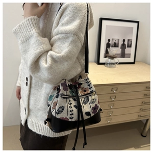 Detail of embroidered floral bucket bag with leather base and drawstring closure