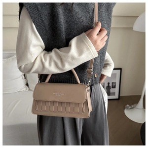 Detail of khaki crossbody bag with woven texture and adjustable shoulder strap worn by model