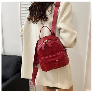 Detail of red embossed PU leather mini backpack with golden zippers and wide strap
