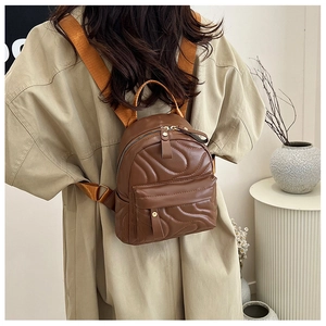 Close-up of a brown quilted mini backpack worn with a stylish beige trench coat