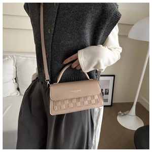 Close-up of beige crossbody bag featuring woven texture detail and a leather handle