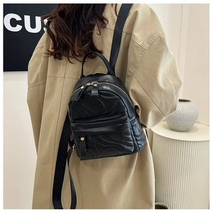Close-up of black mini backpack with quilted wave pattern and gold zipper detail