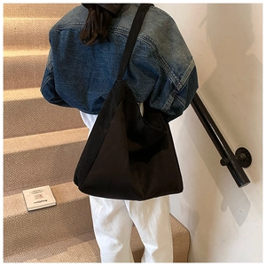 Close-up of the black matte canvas hobo tote bag on the shoulder of a female model