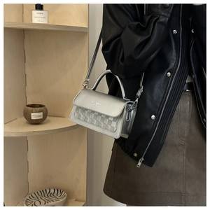 Silver metallic crossbody bag with woven texture worn by model in casual street style