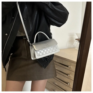 Metallic silver crossbody bag with woven texture worn by model in urban lifestyle setting
