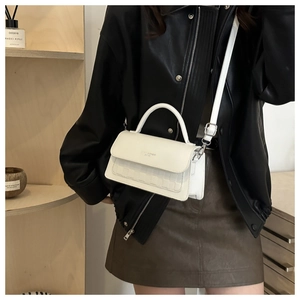 Close-up of white leather plaid crossbody bag with handle and gold strap details