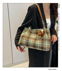 Detail of vintage plaid wool tote bag with brown leather strap and plush monster charm