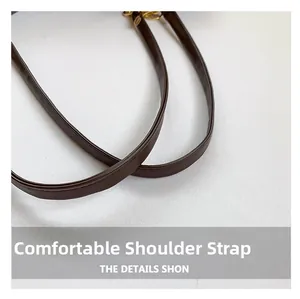 Close-up of smooth brown leather shoulder straps with fine stitching and gold metal hardware