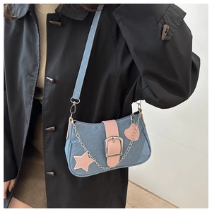 Dettaglio borsa a spalla in denim blu con finiture in pelle rosa e catena con stella