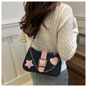 Dettaglio borsa a tracolla in denim blu con stelle rosa e accessorio catena metallica