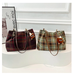Macro detail of plaid tote bags with leather chain straps and plush monster charms
