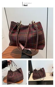 Detail view of red and green plaid tote bag with metal chain and leather handle