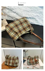 Detail view of plaid tote bag featuring green wool fabric and leather gold chain handles