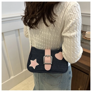 Detalle del bolso denim azul con parches de estrellas rosas y cadena de plata