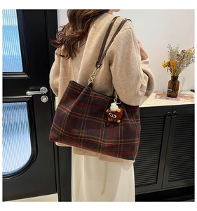 Detail of vintage plaid tote bag with brown leather strap and fuzzy monster charm