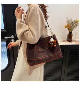Detail of vintage plaid wool shoulder bag with gold chain strap and plush bear charm