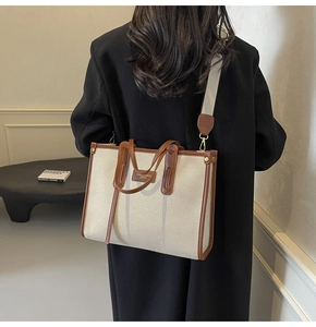 Detail of canvas and brown leather tote bag with wide strap on model back