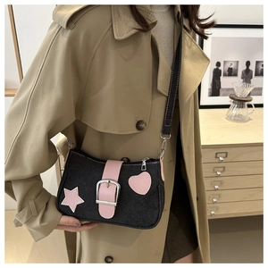 Dettaglio della borsa a spalla in denim con toppe a stella e cuore rosa su modella