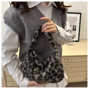 Detail of the soft plush leopard print crescent hobo bag held by a model in a natural setting