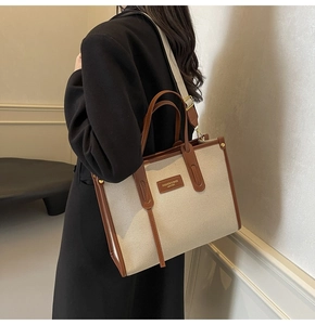 Detail of canvas tote bag with brown leather trim and fashion brand patch