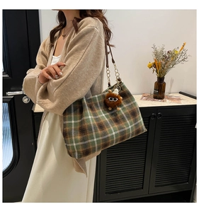 Detail of vintage plaid shoulder bag with brown plush pendant and metal chain strap