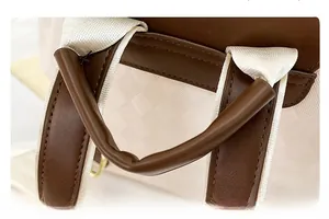 Détail de la poignée en cuir marron et des coutures du tissu à damier crème du sac