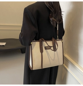 Detail of canvas tote bag with leather trim worn as a shoulder bag by model