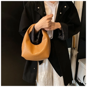 Close-up of brown woven leather hobo bag with intricate texture and curved top handle