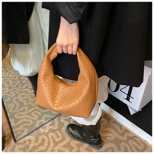 Detail view of woven leather crescent handbag in caramel brown with textured finish