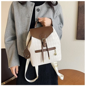 Détail du sac à dos matelassé blanc avec rabat marron et pendentif smiley mignon