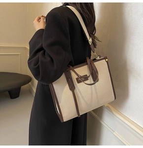 Detail of canvas tote bag showing brown leather handles and adjustable shoulder strap