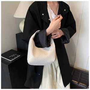 Close-up of white woven leather hobo bag with intricate intrecciato texture and sleek handle