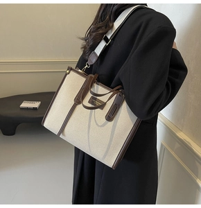 Detail of canvas tote bag with brown leather trim and detachable wide fabric strap