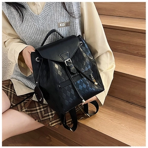 Detailed close-up of a quilted black leather bucket bag with drawstring and smiley charm