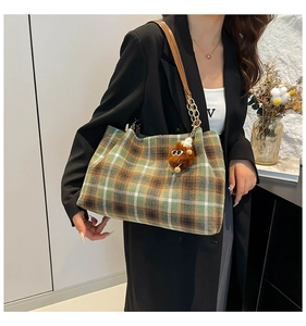 Detail of vintage plaid shoulder bag with brown leather strap and plush charm
