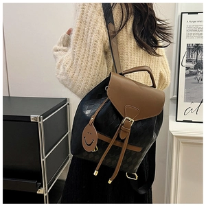 Détail du sac seau matelassé avec fermeture à cordon et breloque visage souriant