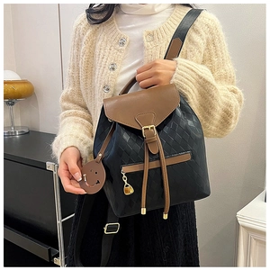 Détail du sac à dos tendance avec texture matelassée, franges et breloque sourire élégante