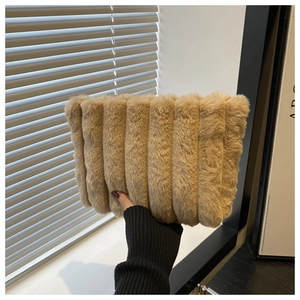 Detailansicht der beigen Plüsch-Clutch mit vertikalen Streifen und weicher Textur