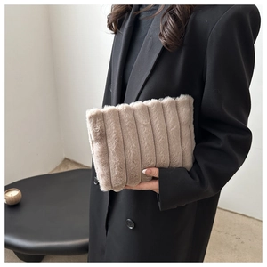 Gros plan d'un sac à main beige en peluche avec texture à rayures et tissu doux