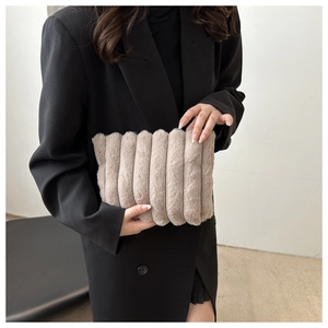 Pochette chic en peluche beige avec texture matelassée verticale tenue par mannequin