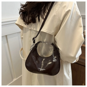 Detail view of coffee leather crescent bag with silver heart charm and metal top handle