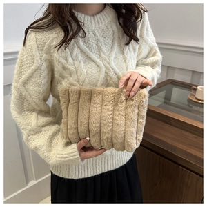 Detail der khakifarbenen Plüsch-Clutch mit vertikaler Streifenstruktur in der Hand