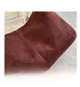 Détail des coutures contrastées sur le sac fourre-tout en daim bordeaux et crème