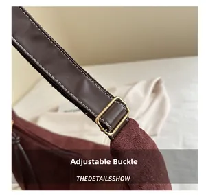 Gros plan sur la boucle réglable dorée d'un sac cabas en daim bordeaux avec bandoulière