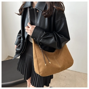 Sac hobo en daim marron avec cordons latéraux porté par un mannequin en cuir